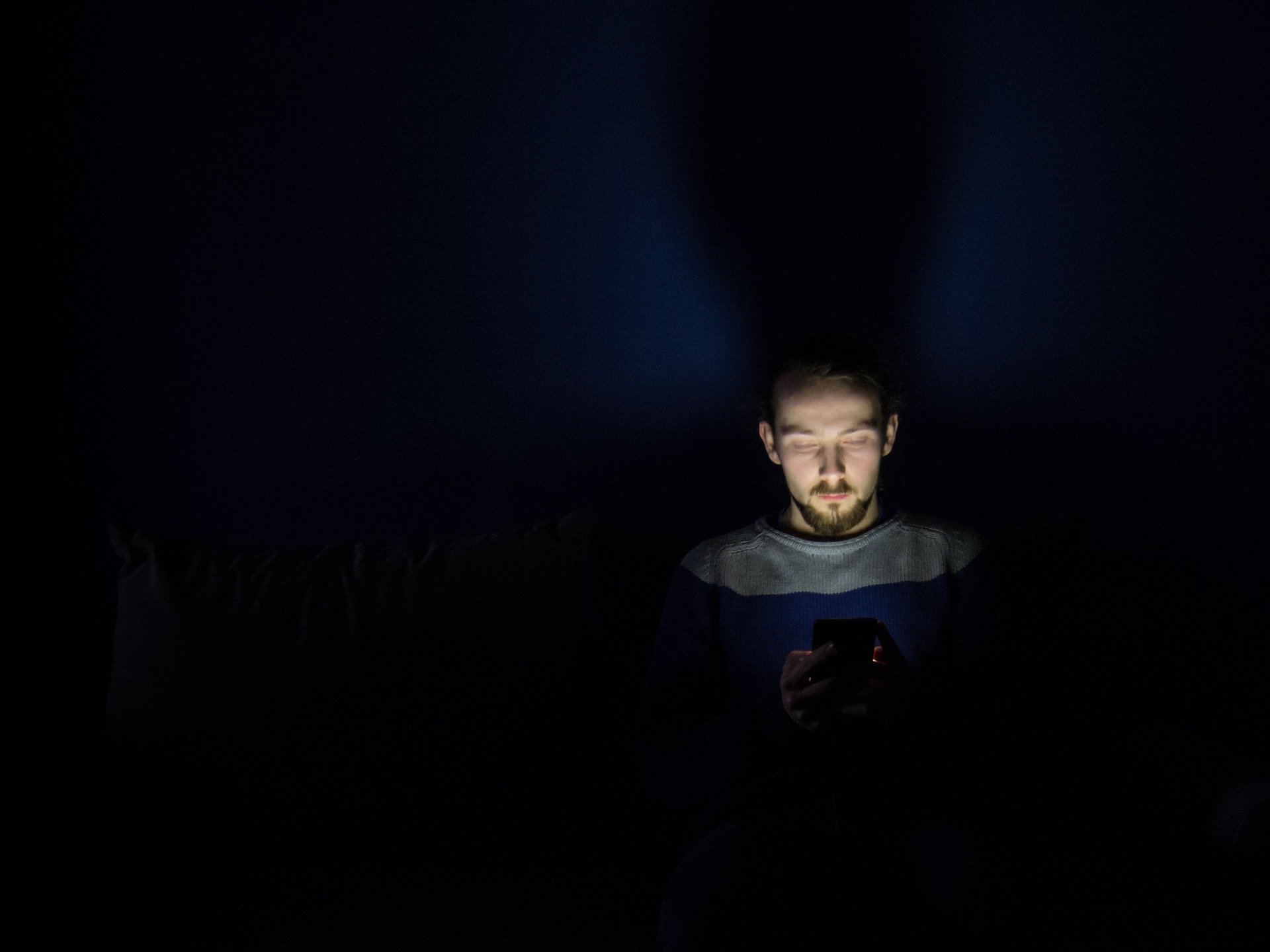 man using phone in darkness